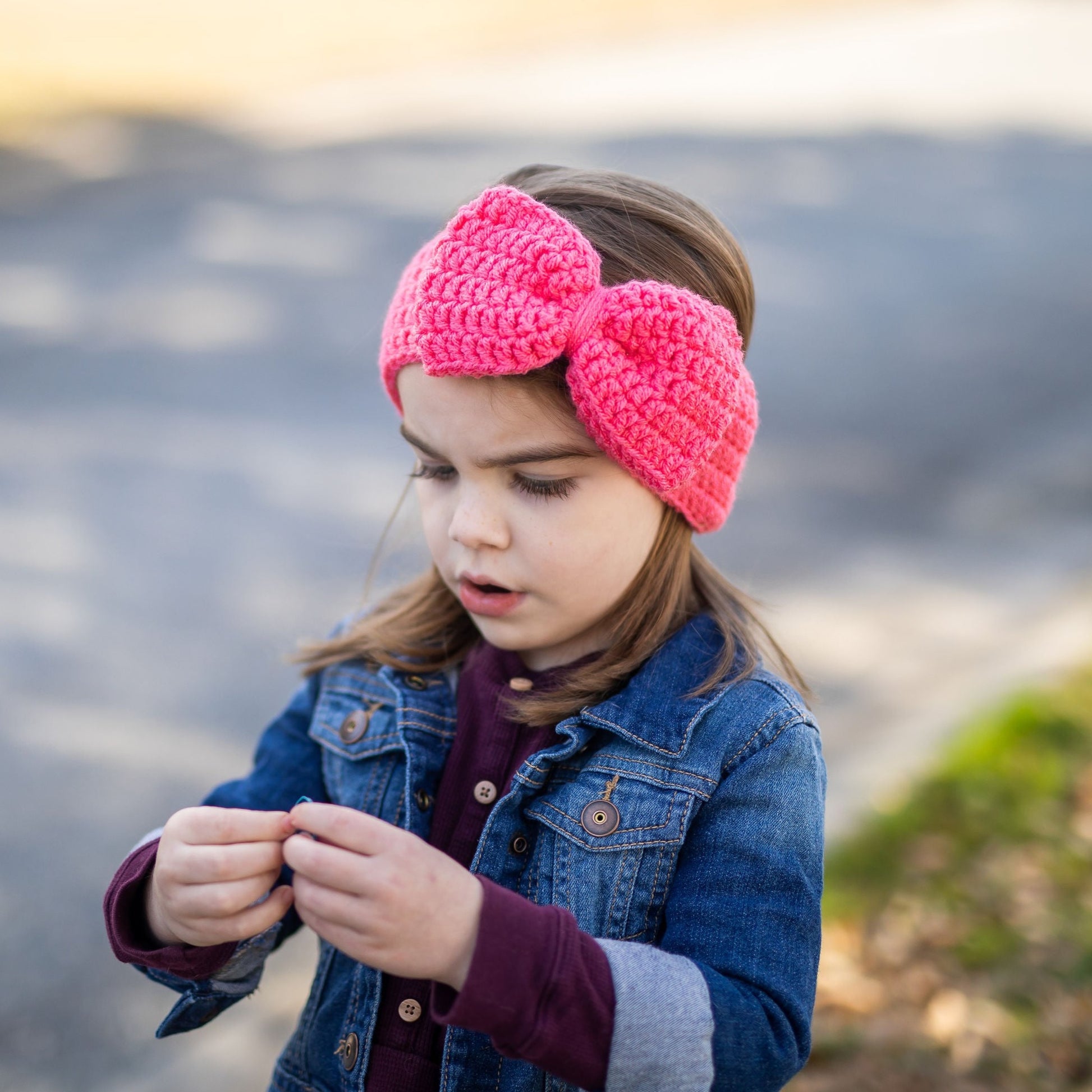 girl wearing a coral pink big bow ear warmer headband