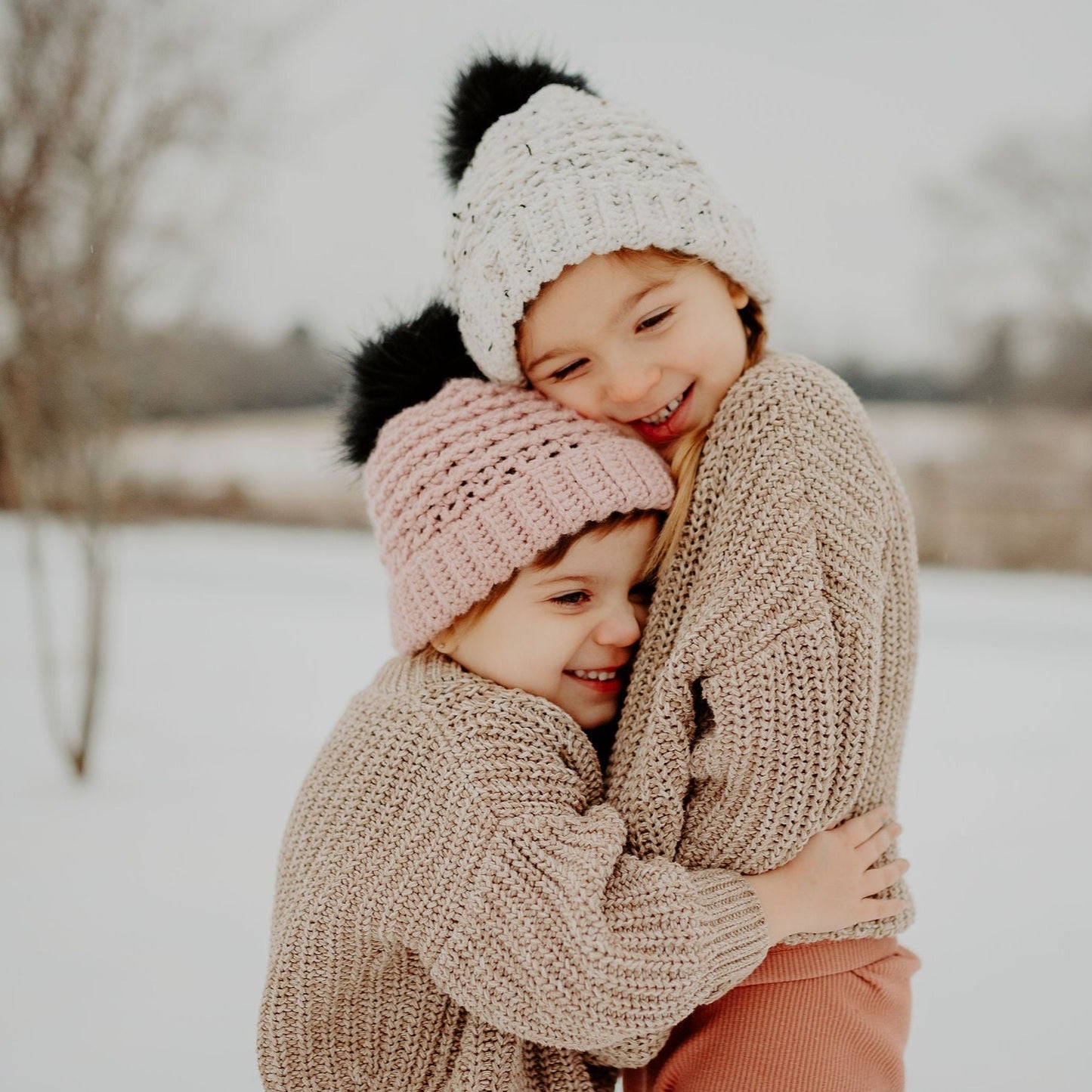 Tweed and blush double brim winter beanie with a black faux fur pom pom. 