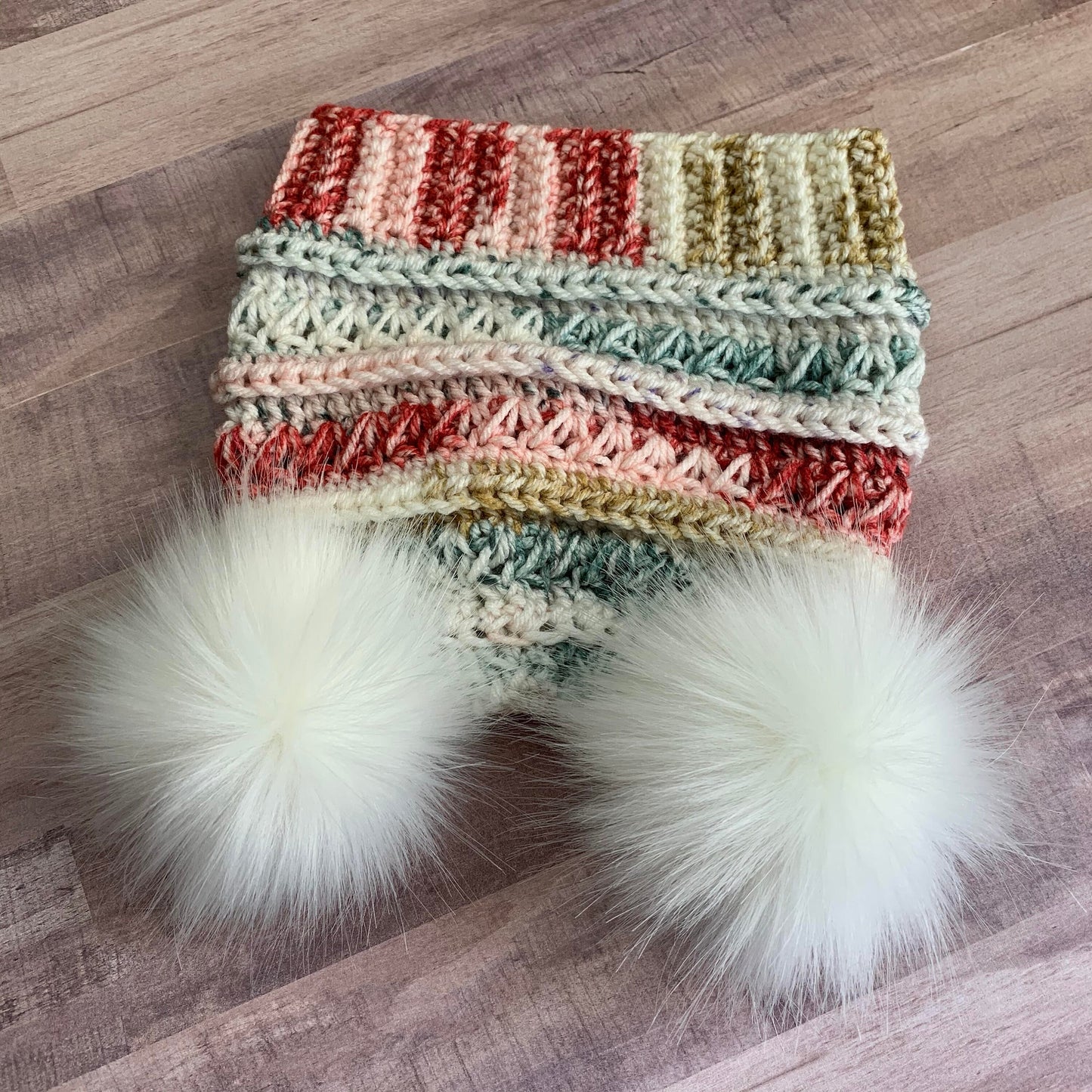 Multicolored beanie with two white faux fur pom poms