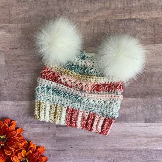 Multicolored beanie with two white faux fur pom poms