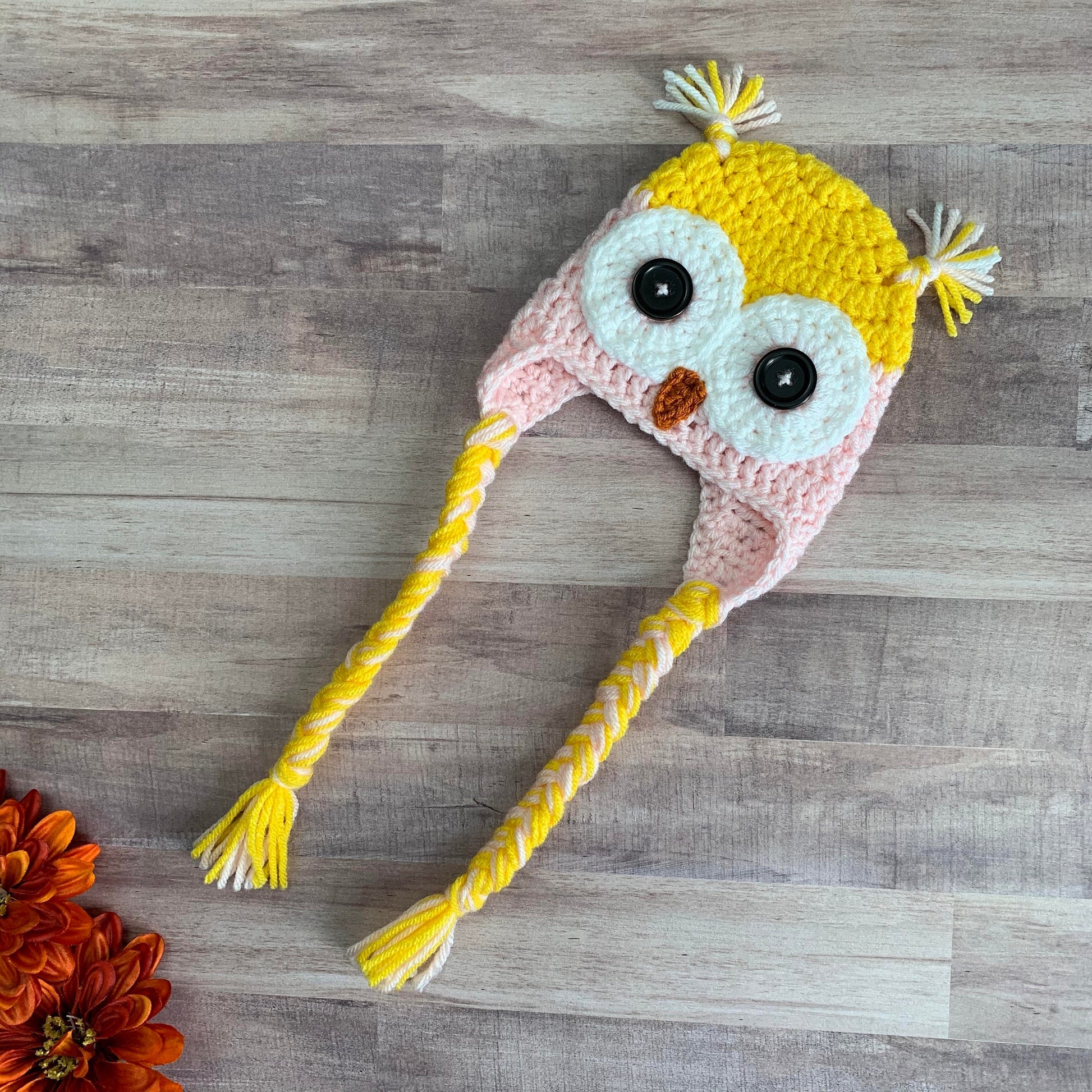 yellow and pink owl beanie flat lay on a wood background