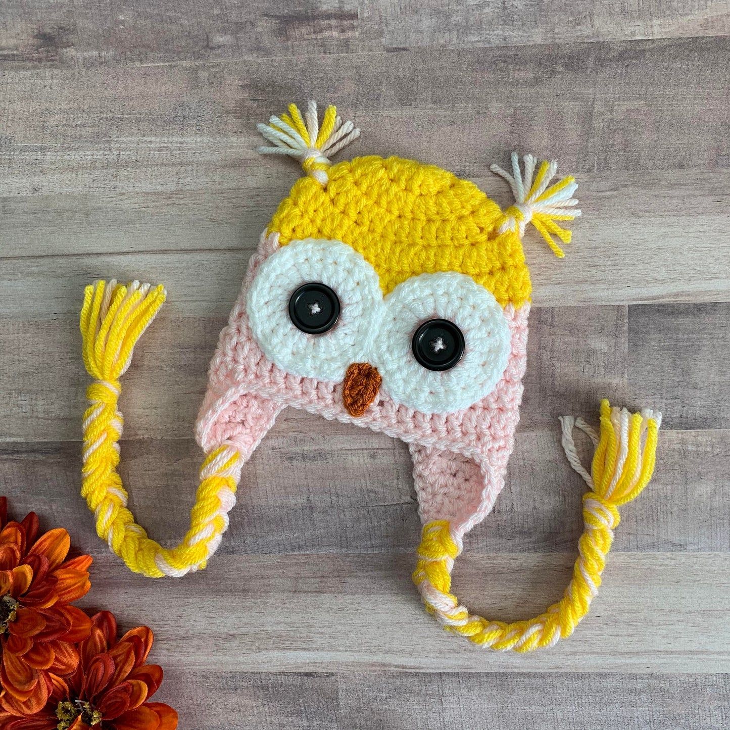 yellow and pink owl beanie flat lay on a wood background