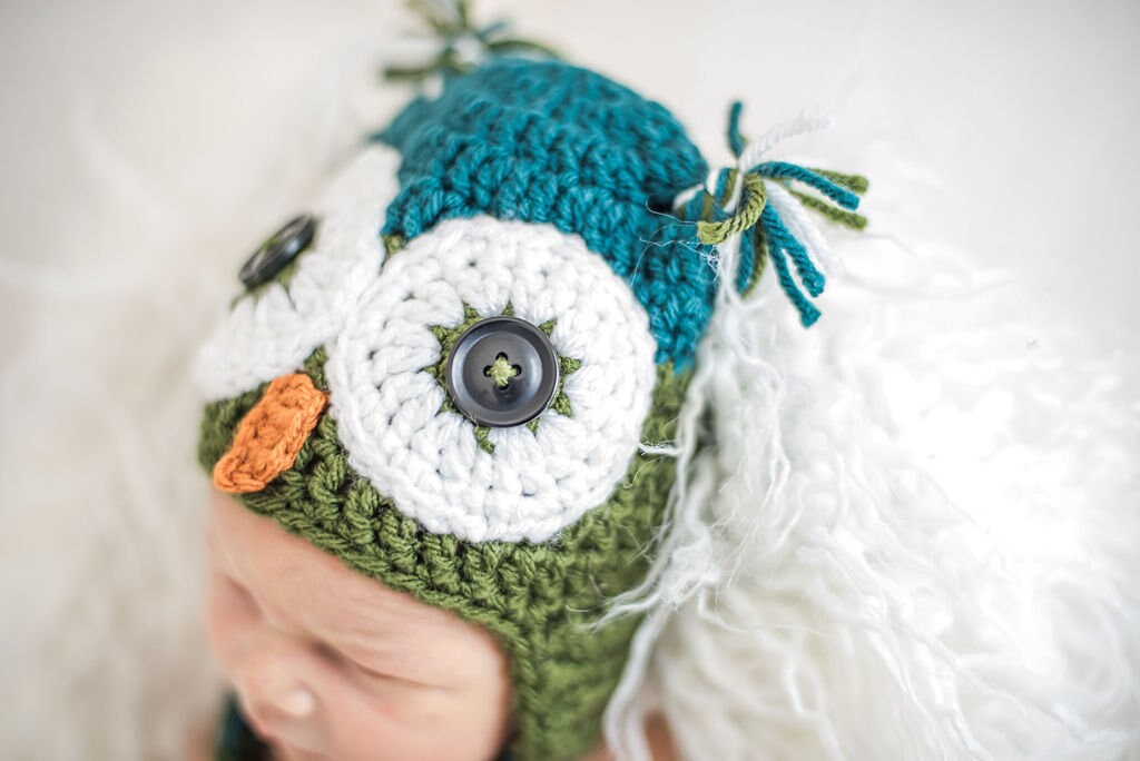 close up of the owl eyes on a teal and olive green owl beanie