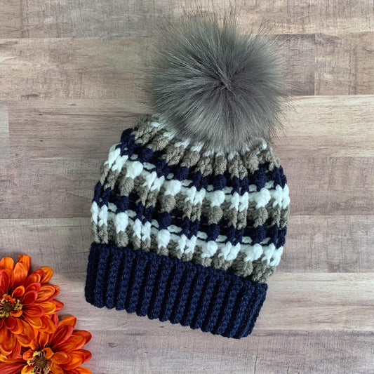 Navy, white and grey beanie with a grey faux fur pom pom