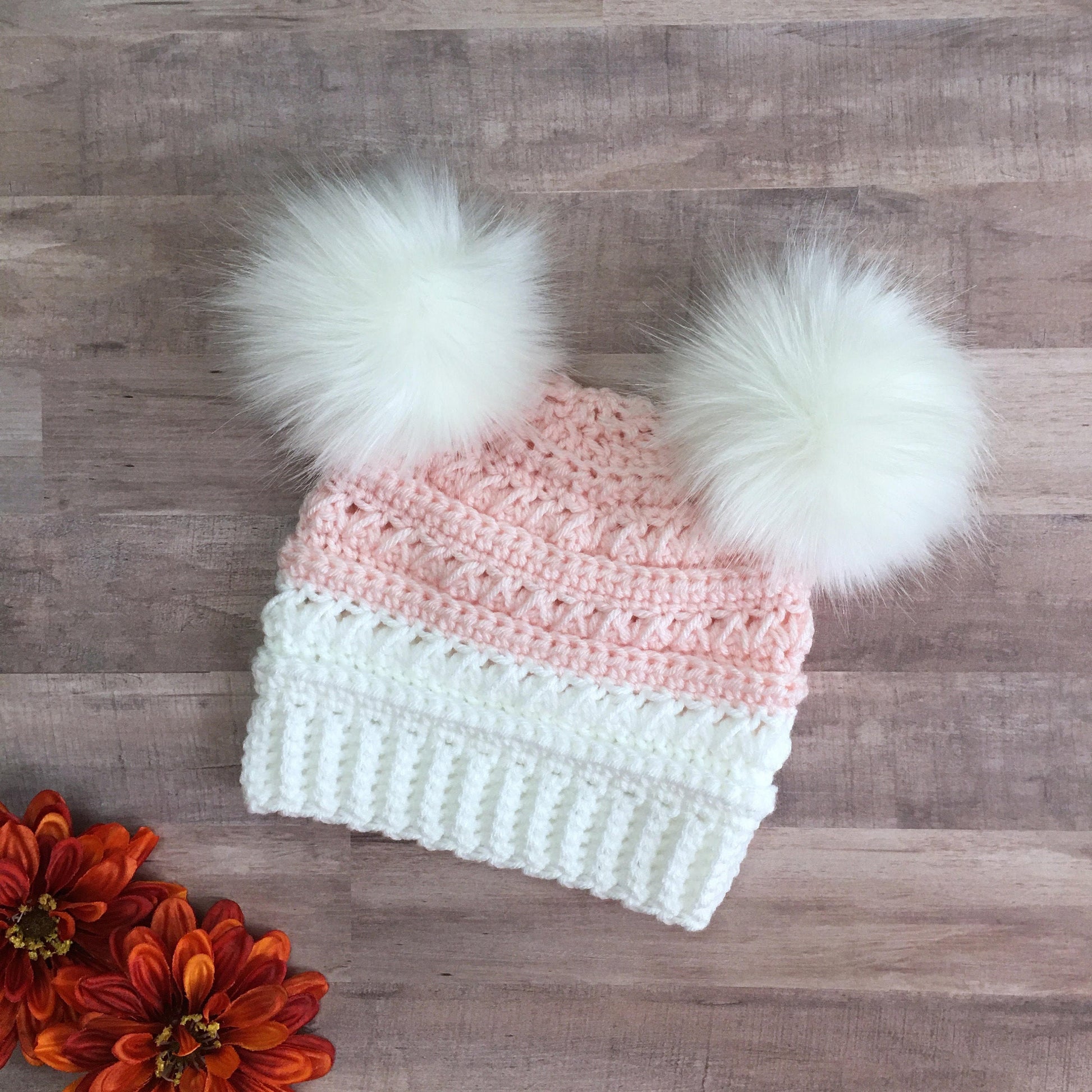 White and pink beanie with two white faux fur pom poms