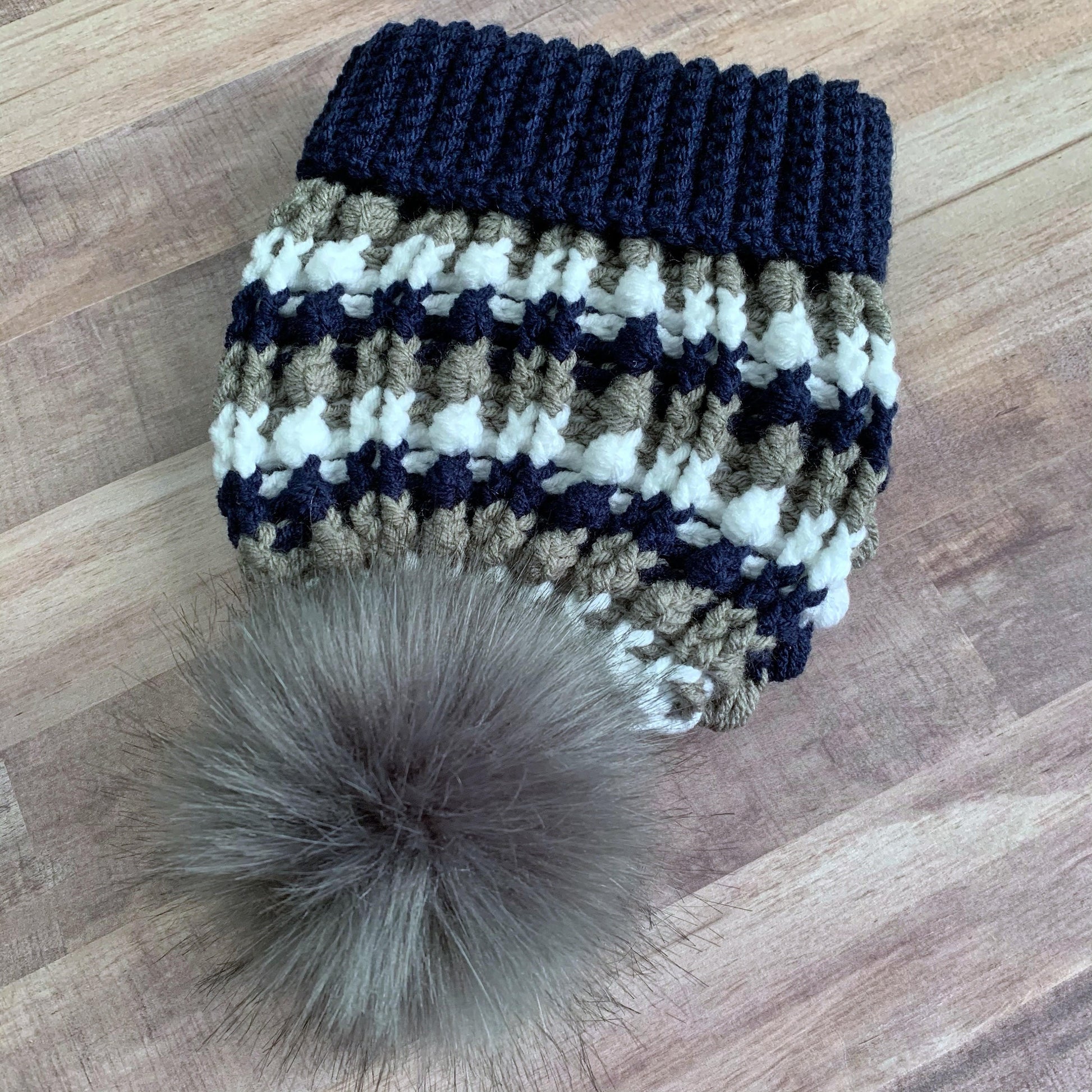 Navy, white and grey beanie with a grey faux fur pom pom