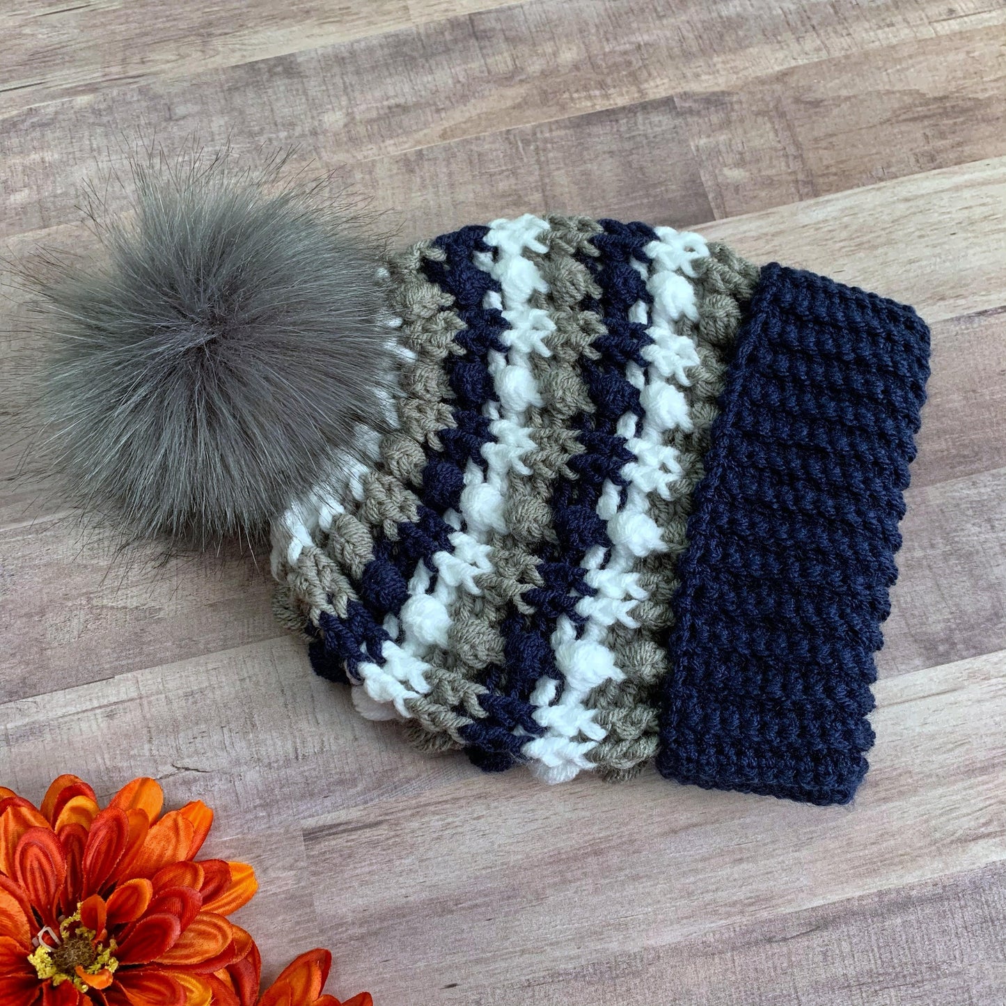 Navy, white and grey beanie with a grey faux fur pom pom