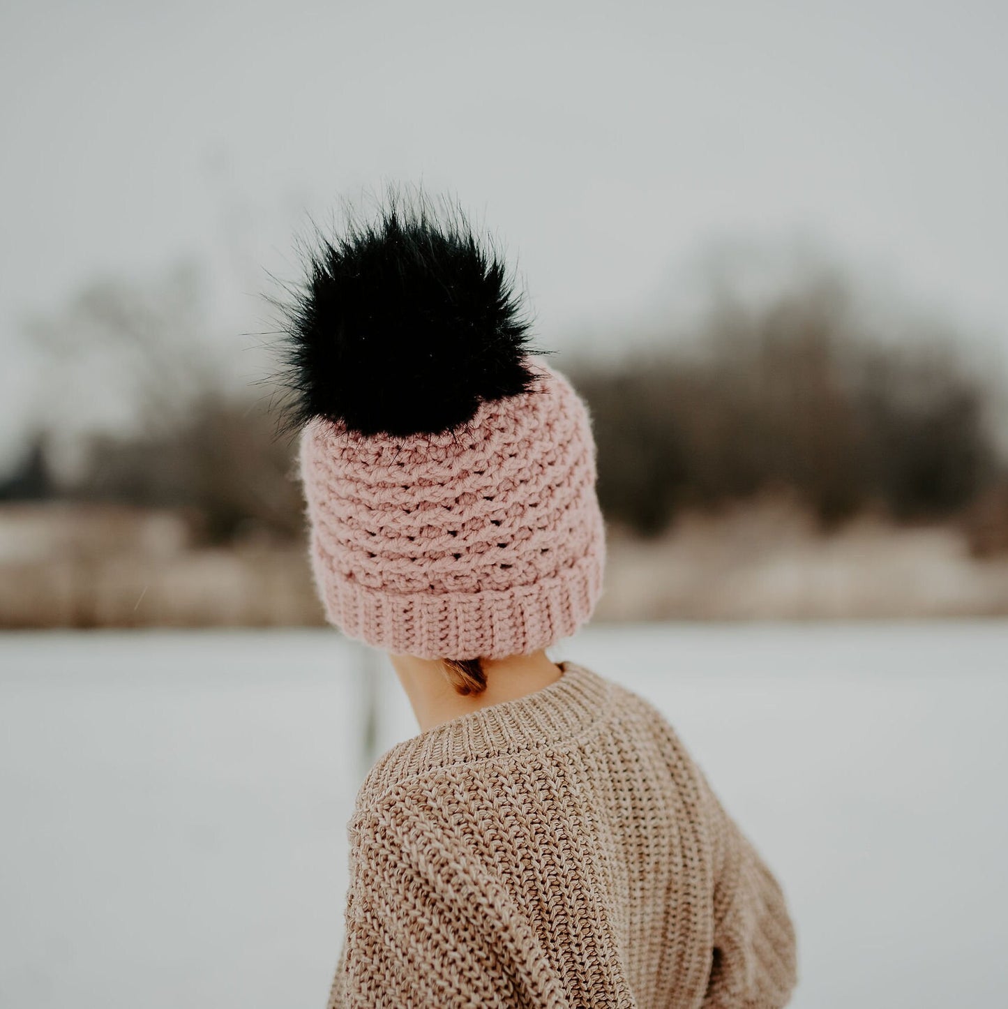 Back view of the blush double brim beanie with a black faux fur pom pom