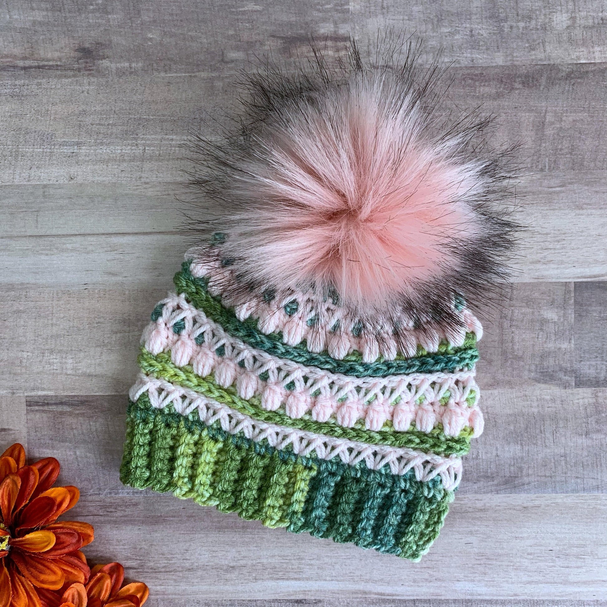 Green and pink beanie with pink faux fur pom pom