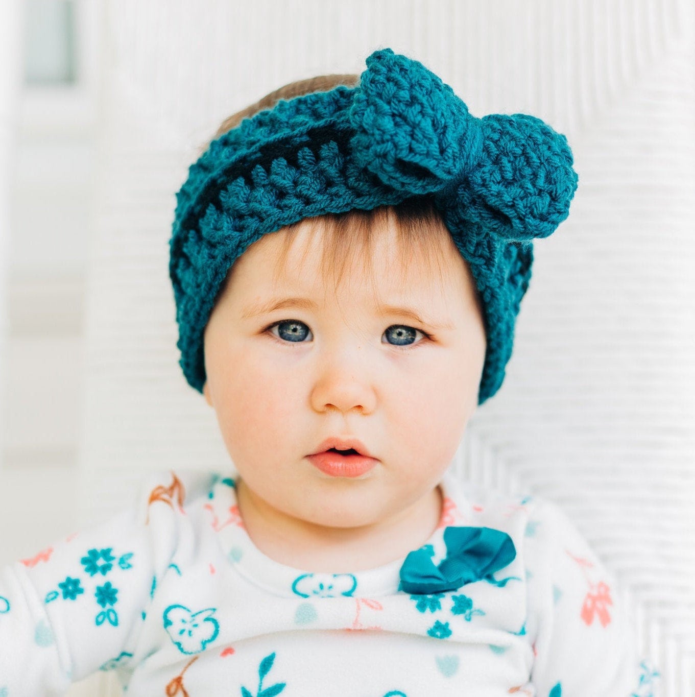 Baby wearing a teal and black bow ear warmer 