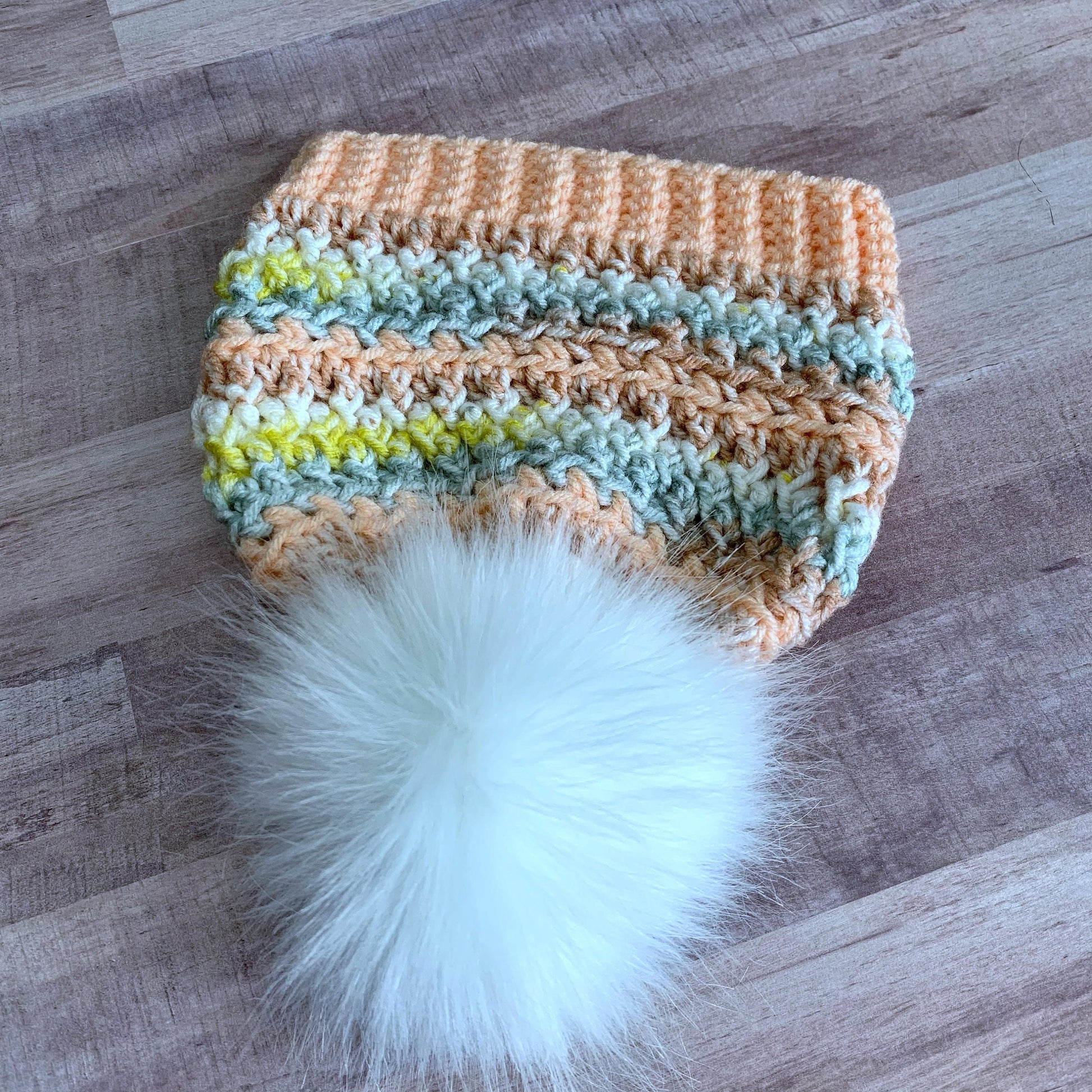 Colorful peach beanie with a white faux fur pom pom