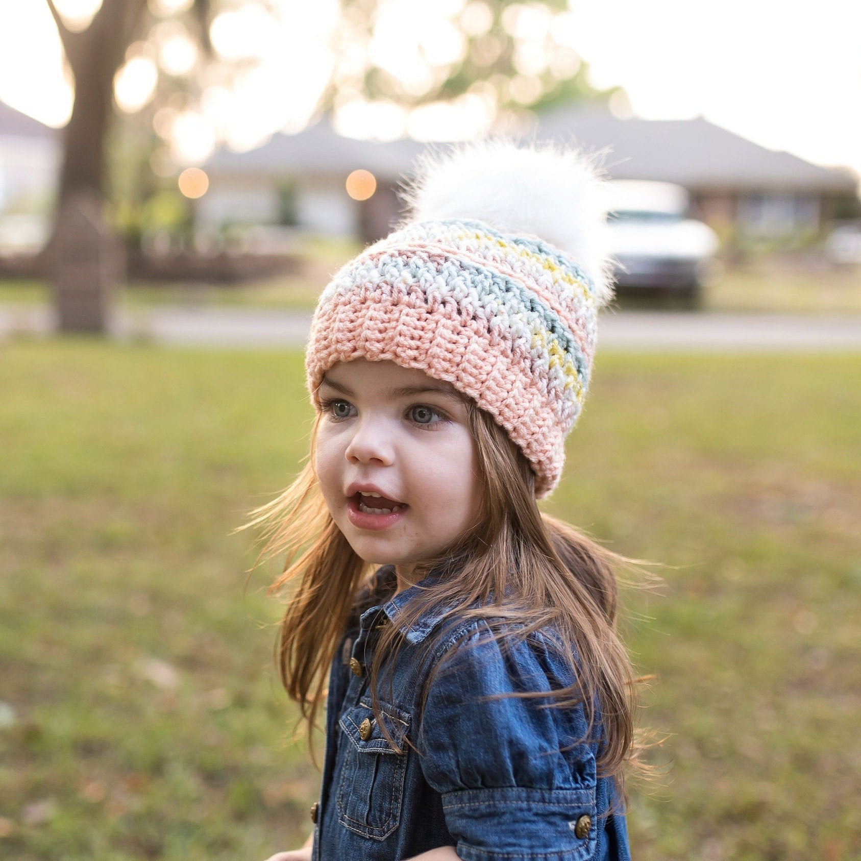 Colorful peach beanie with a white faux fur pom pom