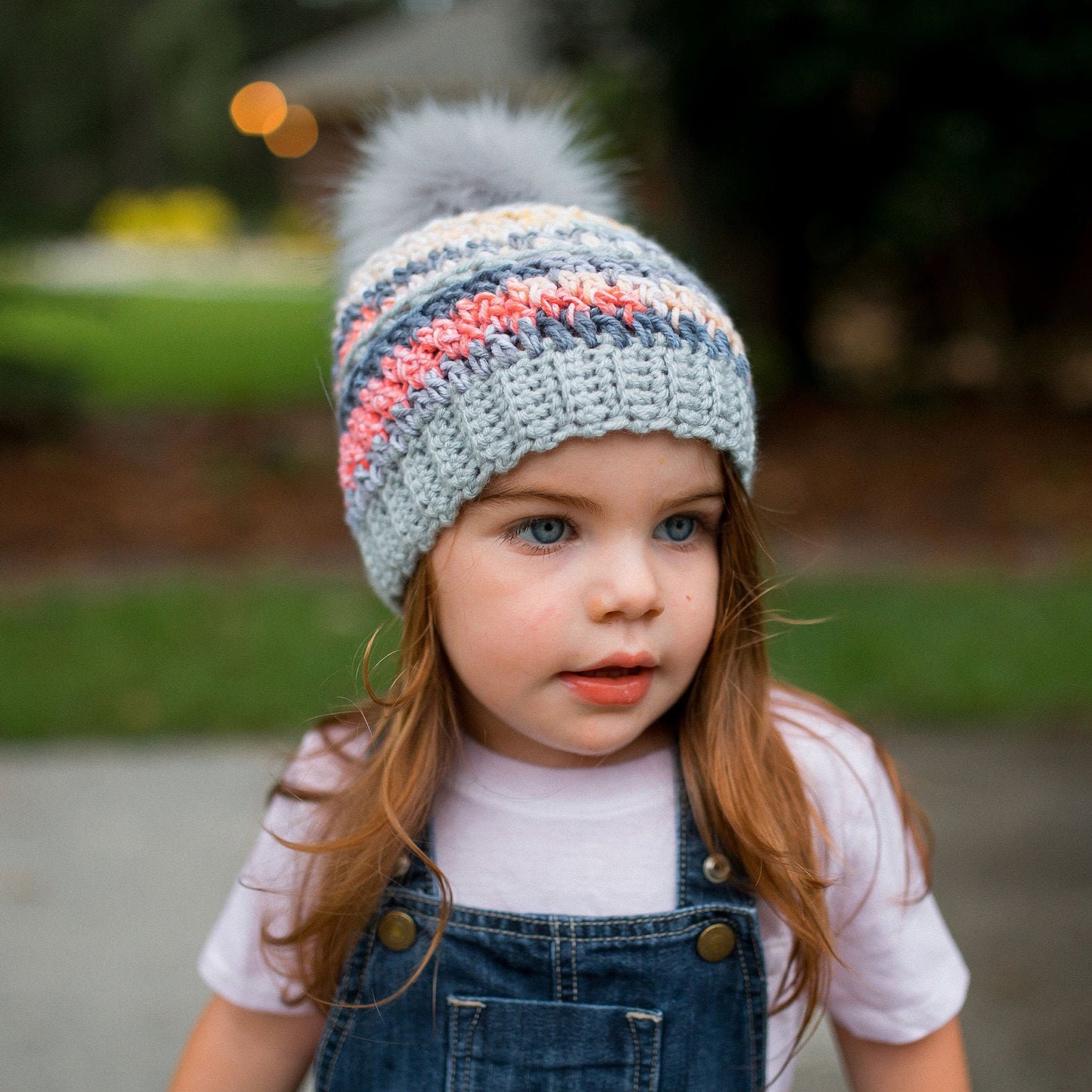 Grey rainbow beanie with a light grey faux fur pom pom