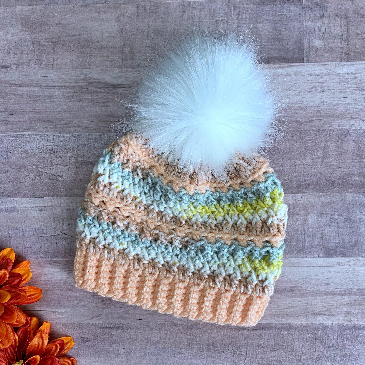 Colorful peach beanie with a white faux fur pom pom