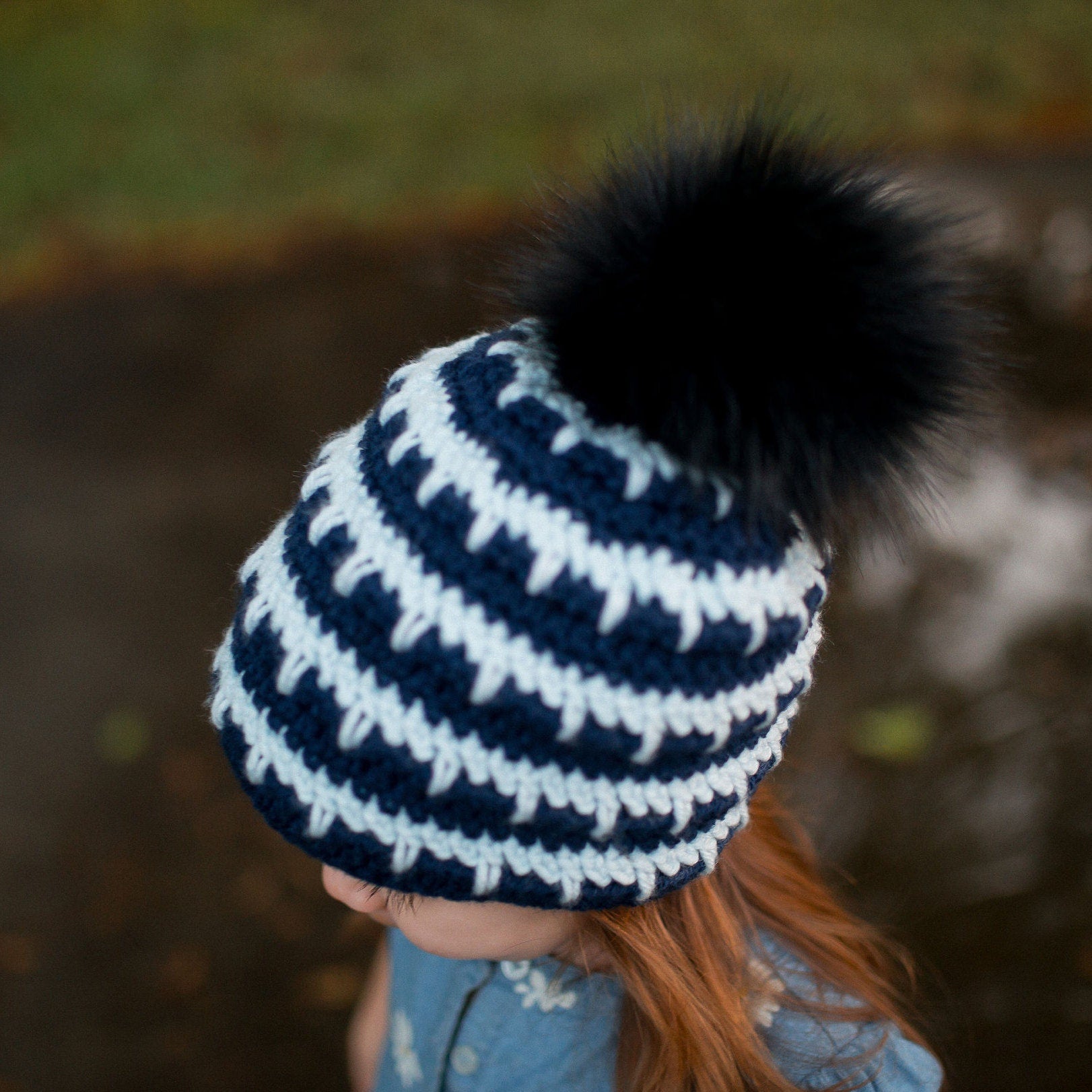 Top down view of navy and arctic ice striped beanie with a black pom pom