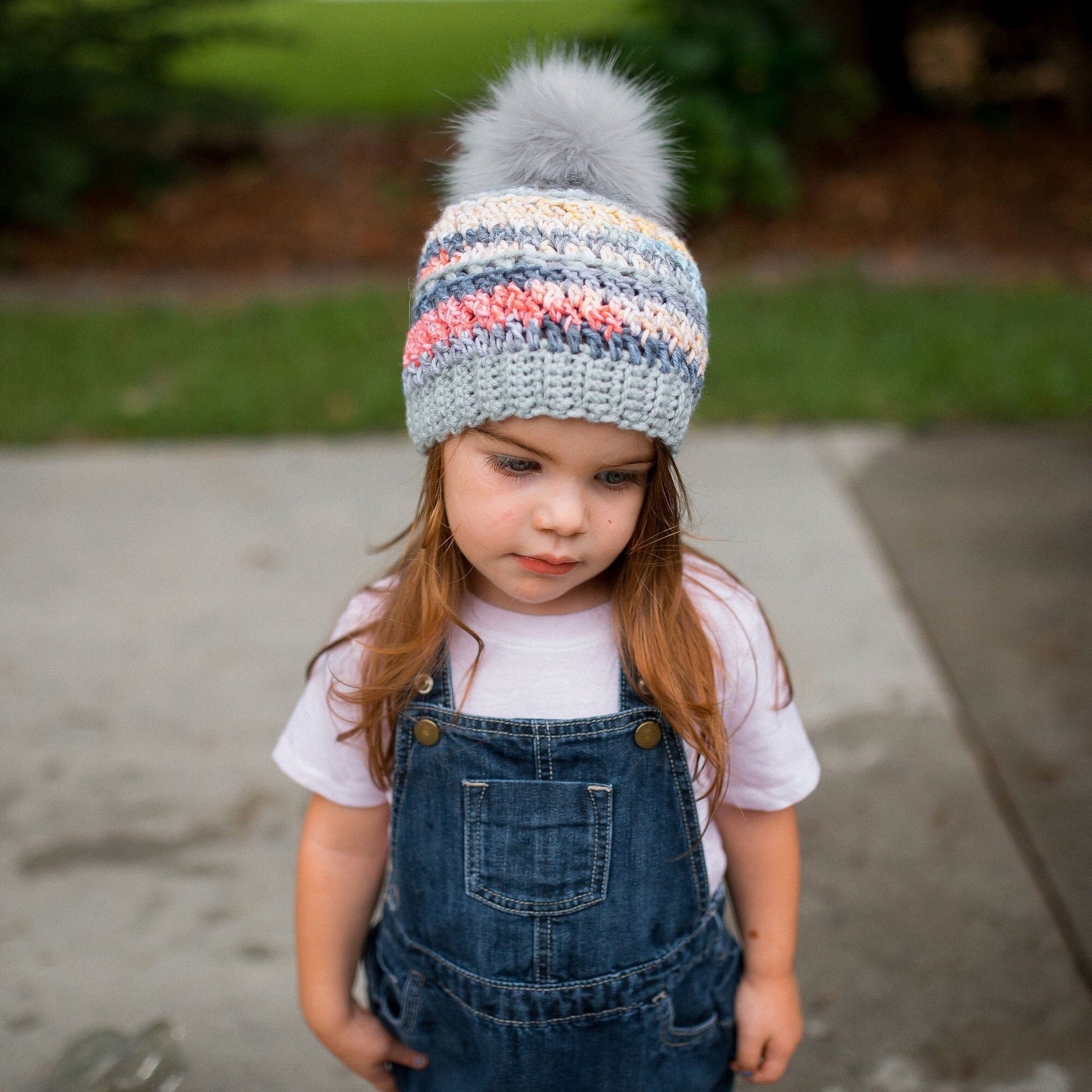 Grey rainbow beanie with a light grey faux fur pom pom