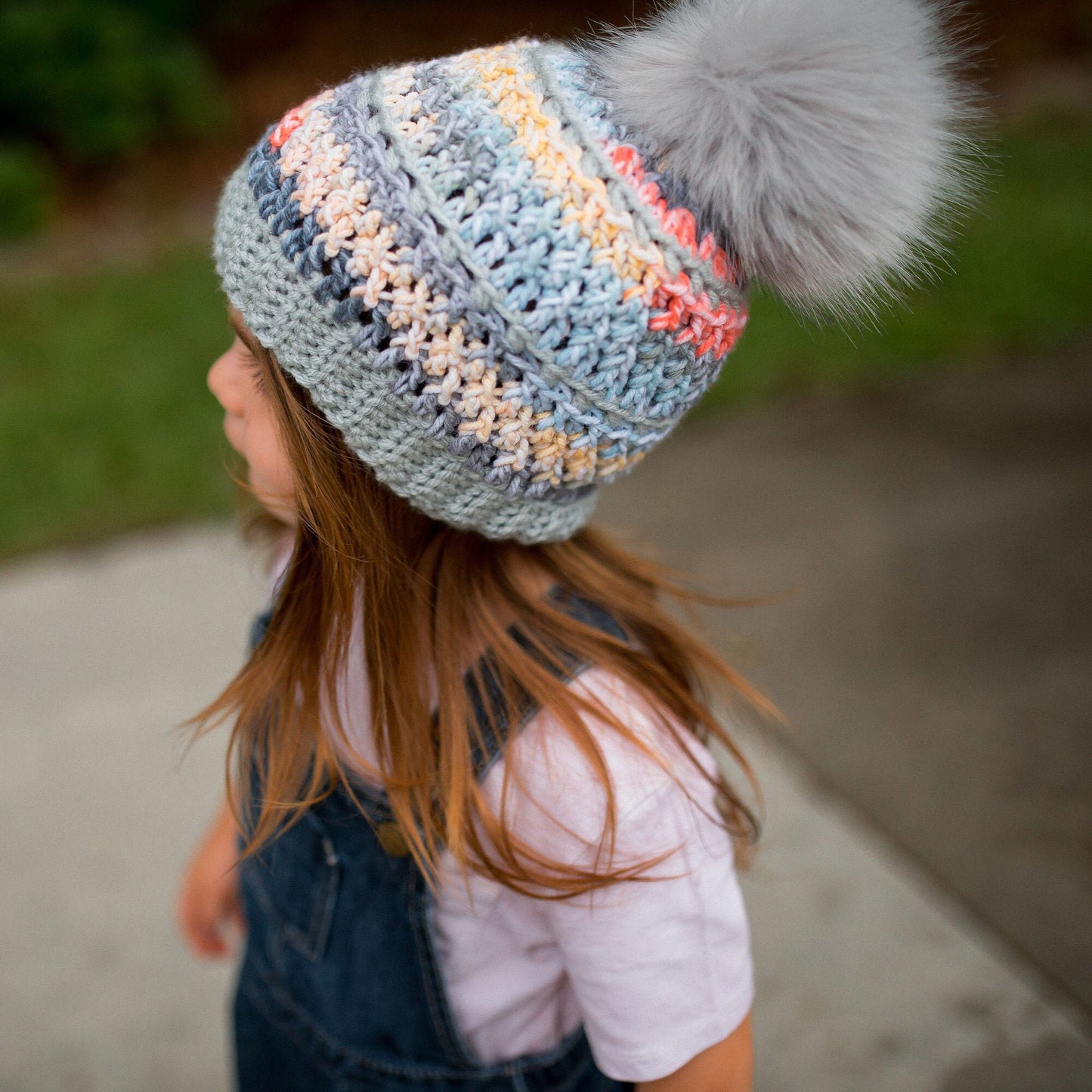 Grey rainbow beanie with a light grey faux fur pom pom