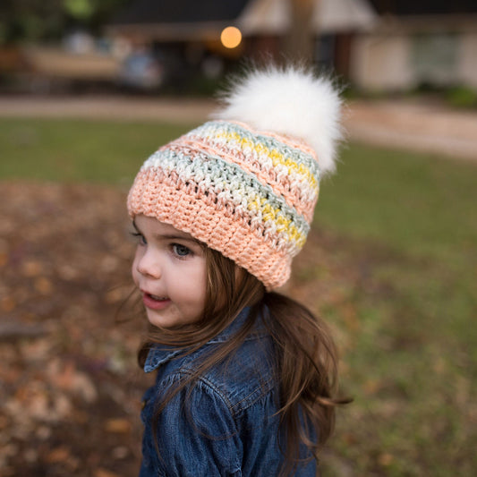 Colorful peach beanie with a white faux fur pom pom