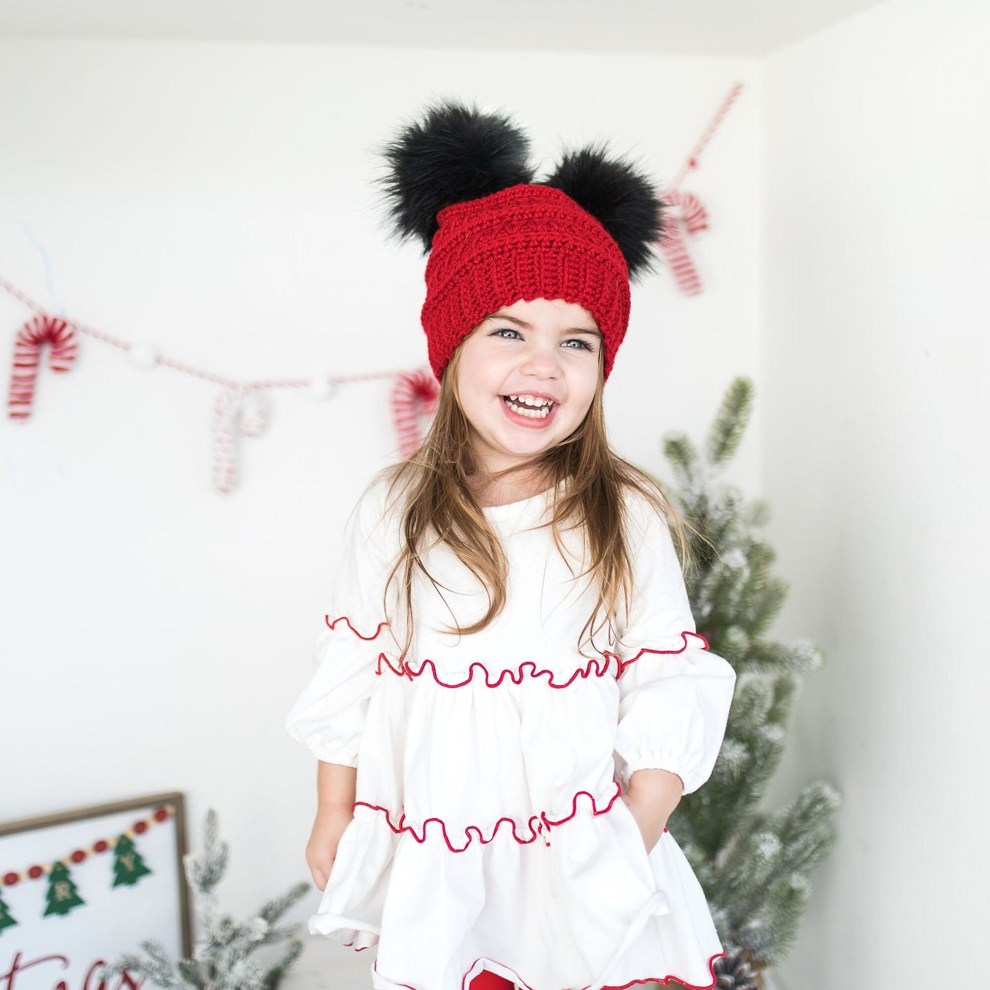 Red beanie with two black faux fur pom poms