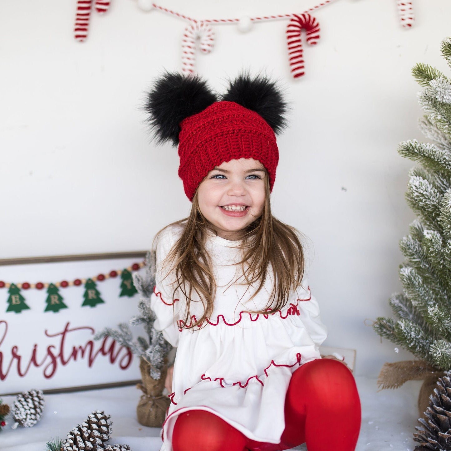 Red beanie with two black faux fur pom poms