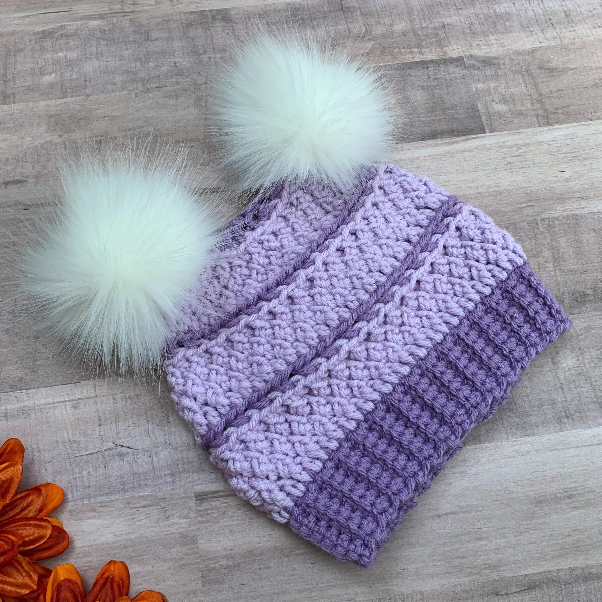 Purple beanie with two white faux fur pom poms