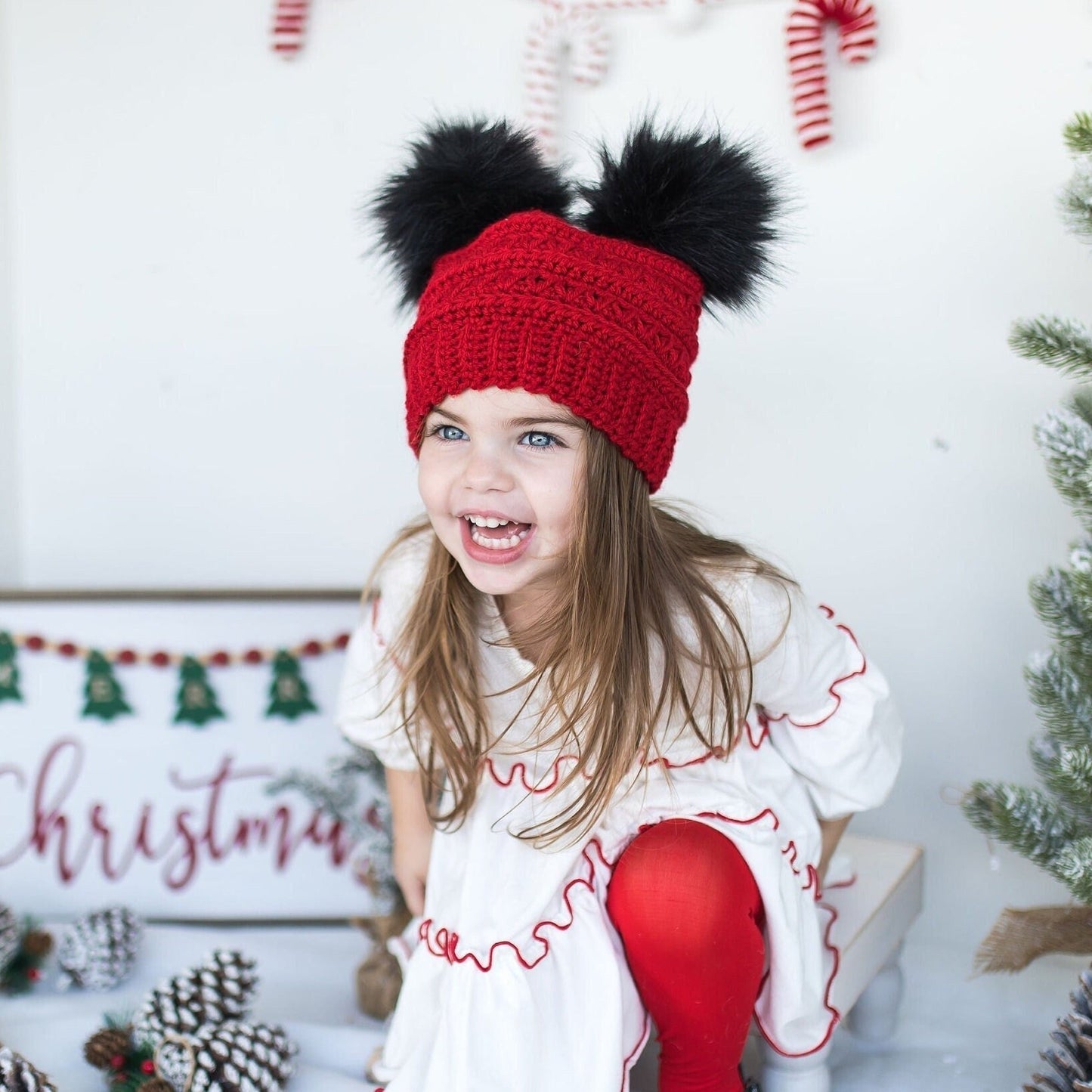 Red beanie with two black faux fur pom poms