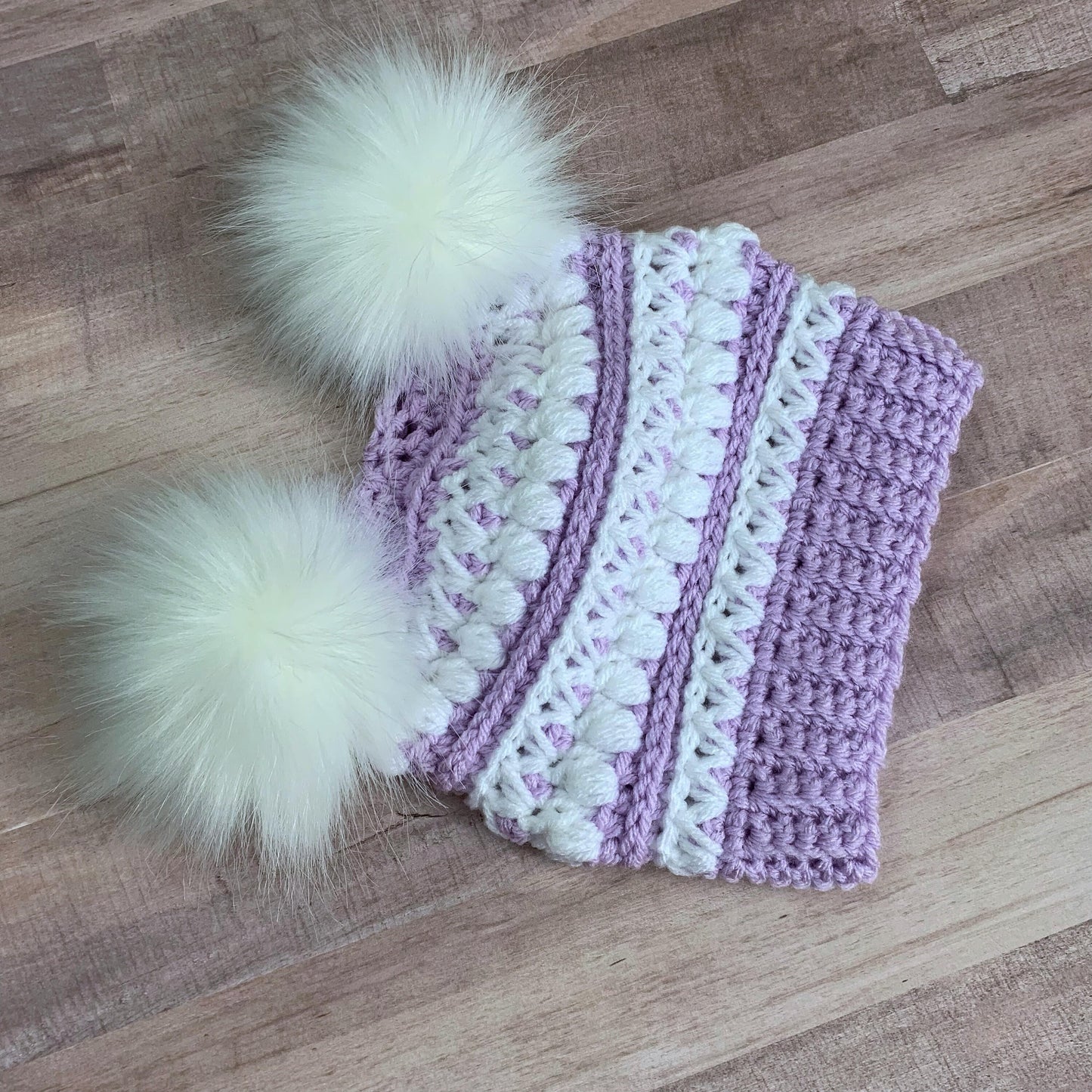 Purple and white beanie with two white faux fur pom poms