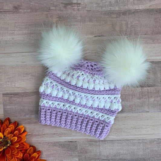 Purple and white beanie with two white faux fur pom poms