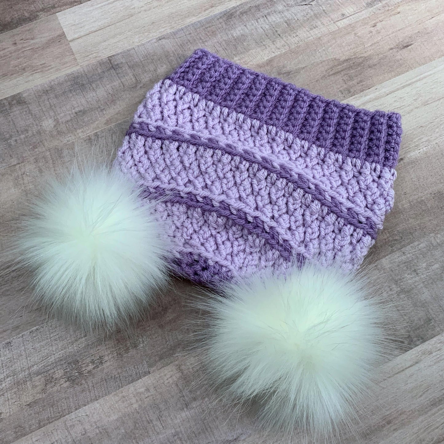 Purple beanie with two white faux fur pom poms