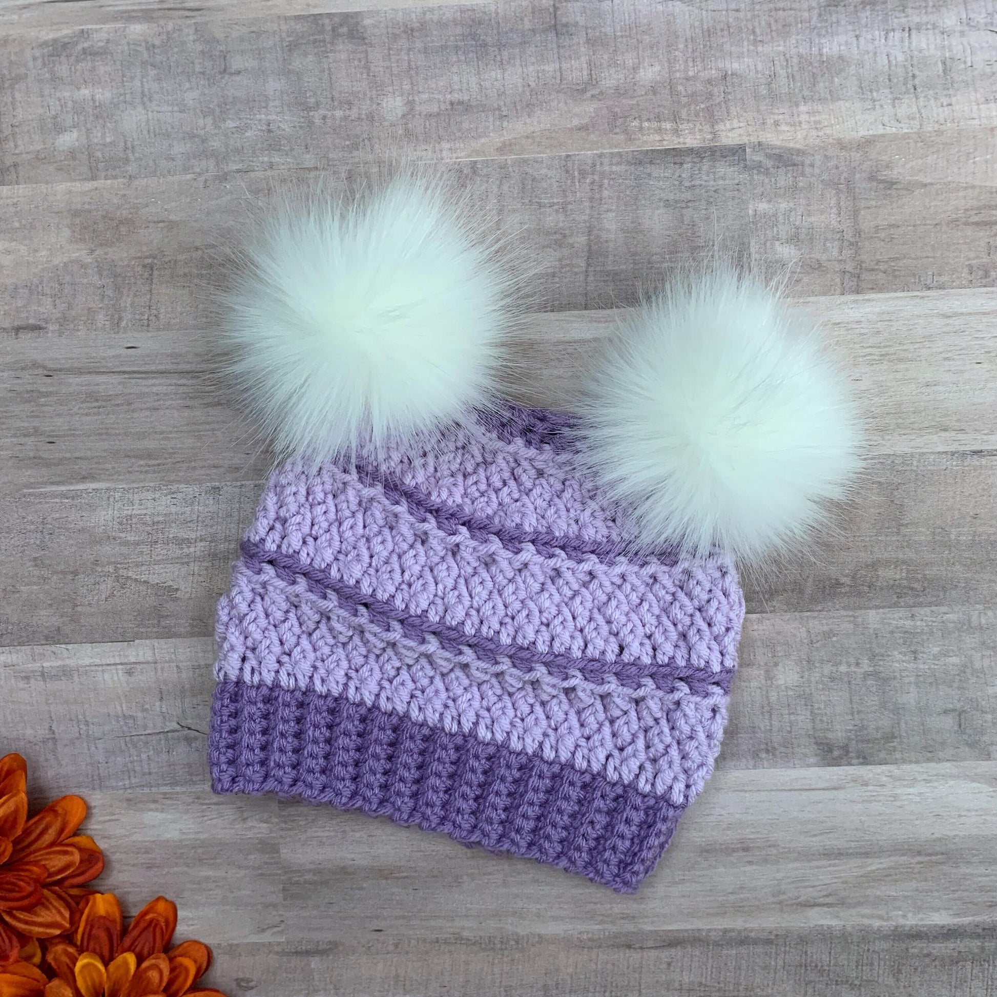 Purple beanie with two white faux fur pom poms