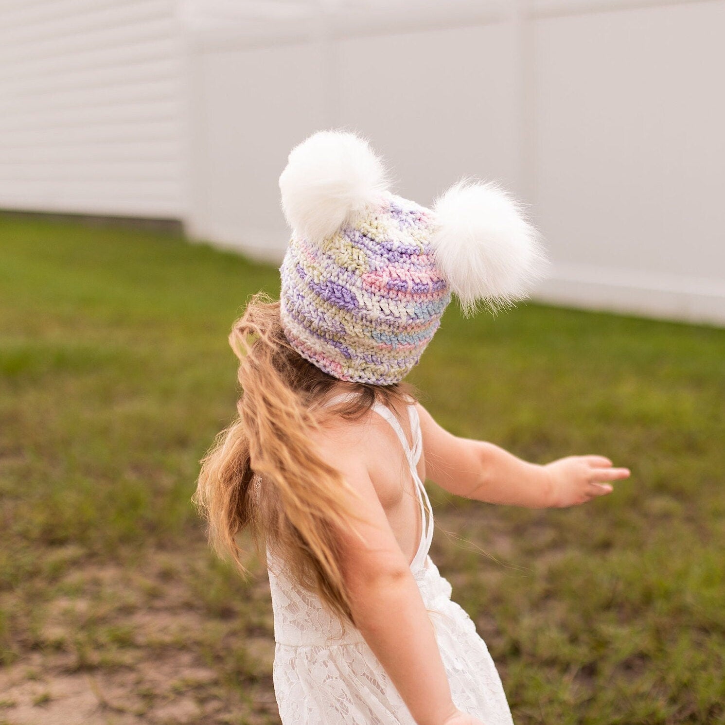 Pastel beanie with two white faux fur pom poms