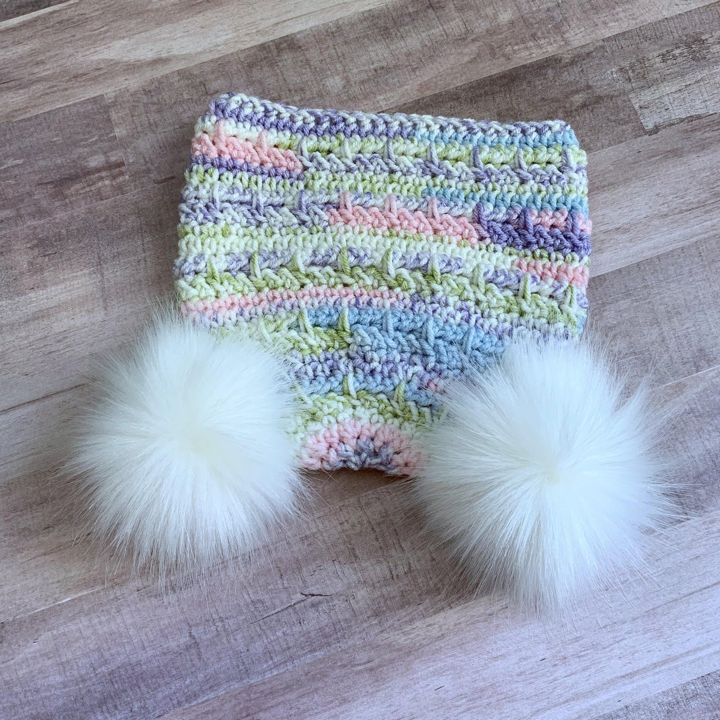 Pastel beanie with two white faux fur pom poms