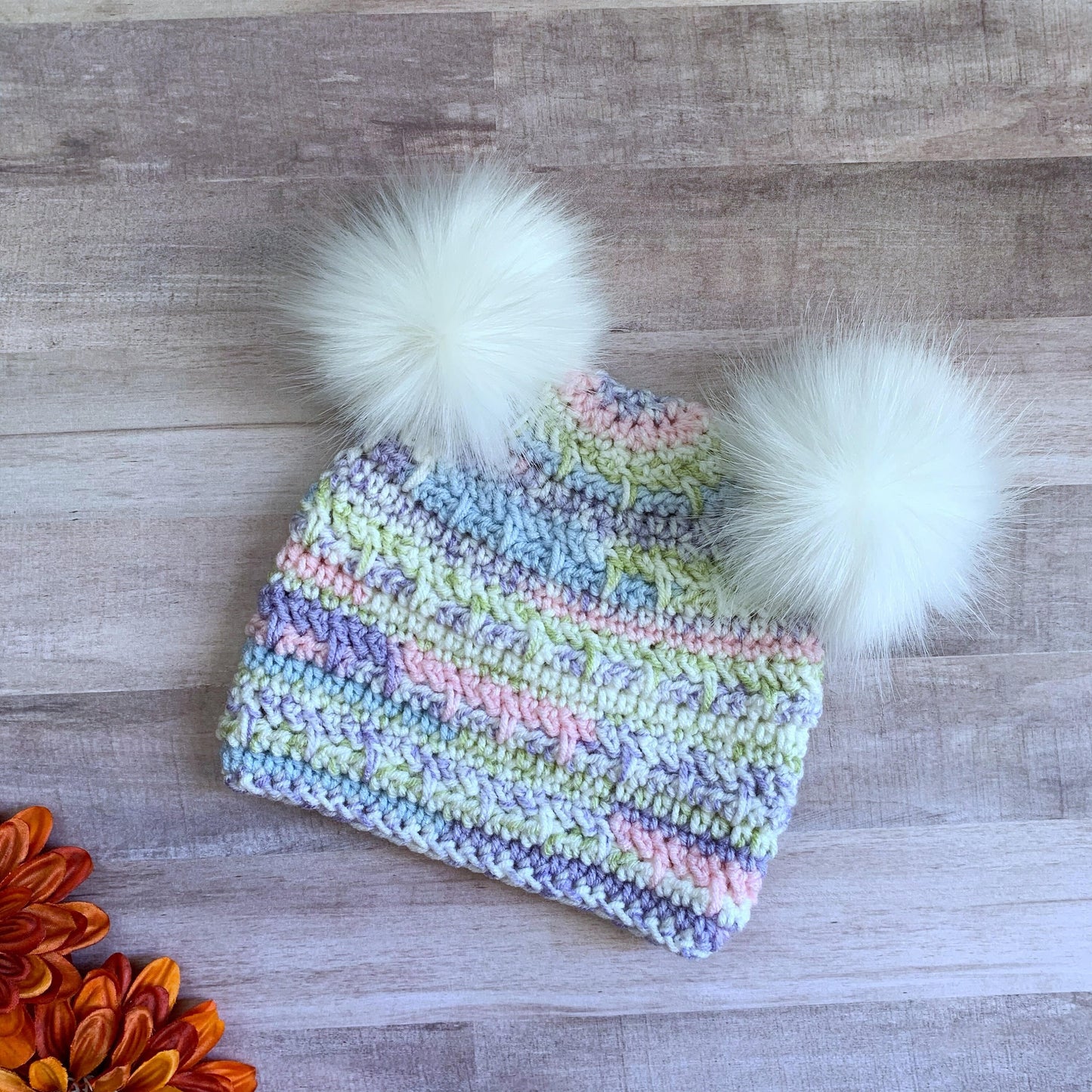 Pastel beanie with two white faux fur pom poms