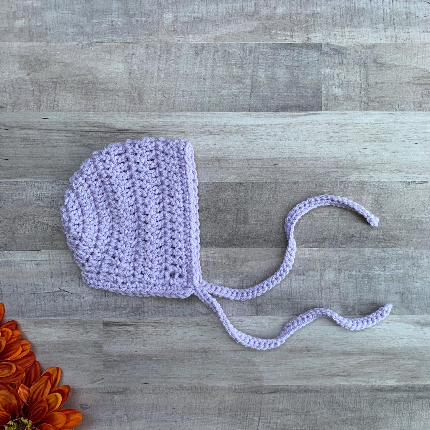 lavender bonnet flat lay on a wood background