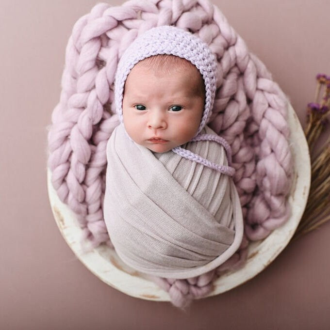 newborn baby in a lavender bonnet