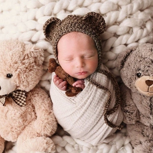 Baby in a bear bonnet surrounded by bear stuffed animals